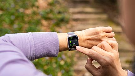 Woman outside checking activity on Apple Watch.