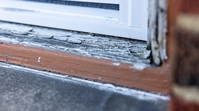 An image of a door threshold that has pealing paint.